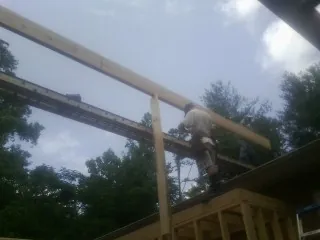 Carpenter setting a ridge beam over a new addition frame — Ice Dam Removal by Roofing Brothers in Mustang