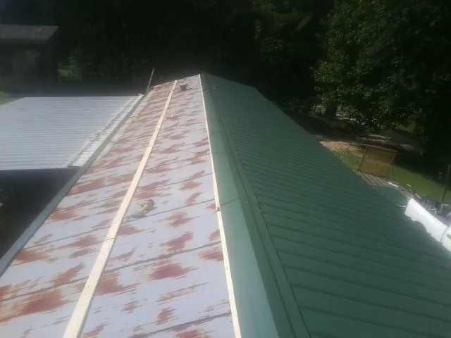 Old rusted panels beside newly installed green metal roofing — Wind Damage Roof Repair by Roofing Brothers in Mustang