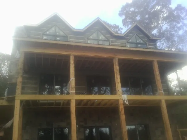 Dormers and porch framing on a large log home under construction — Roof Coating work by our crew in Mustang