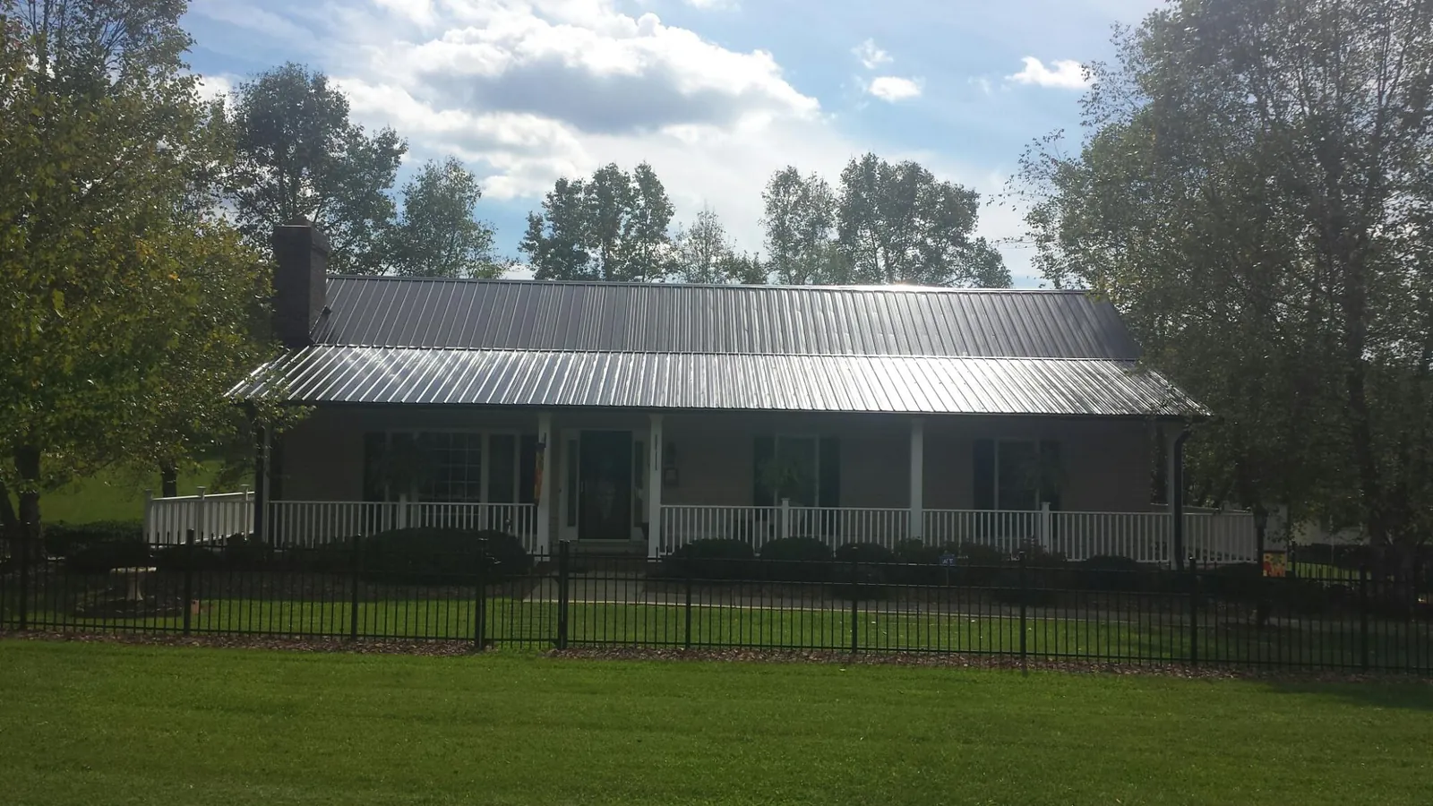 Gray metal roof on a brick ranch with a full width front porch — Gutter Guard Installation work by our crew in Mustang