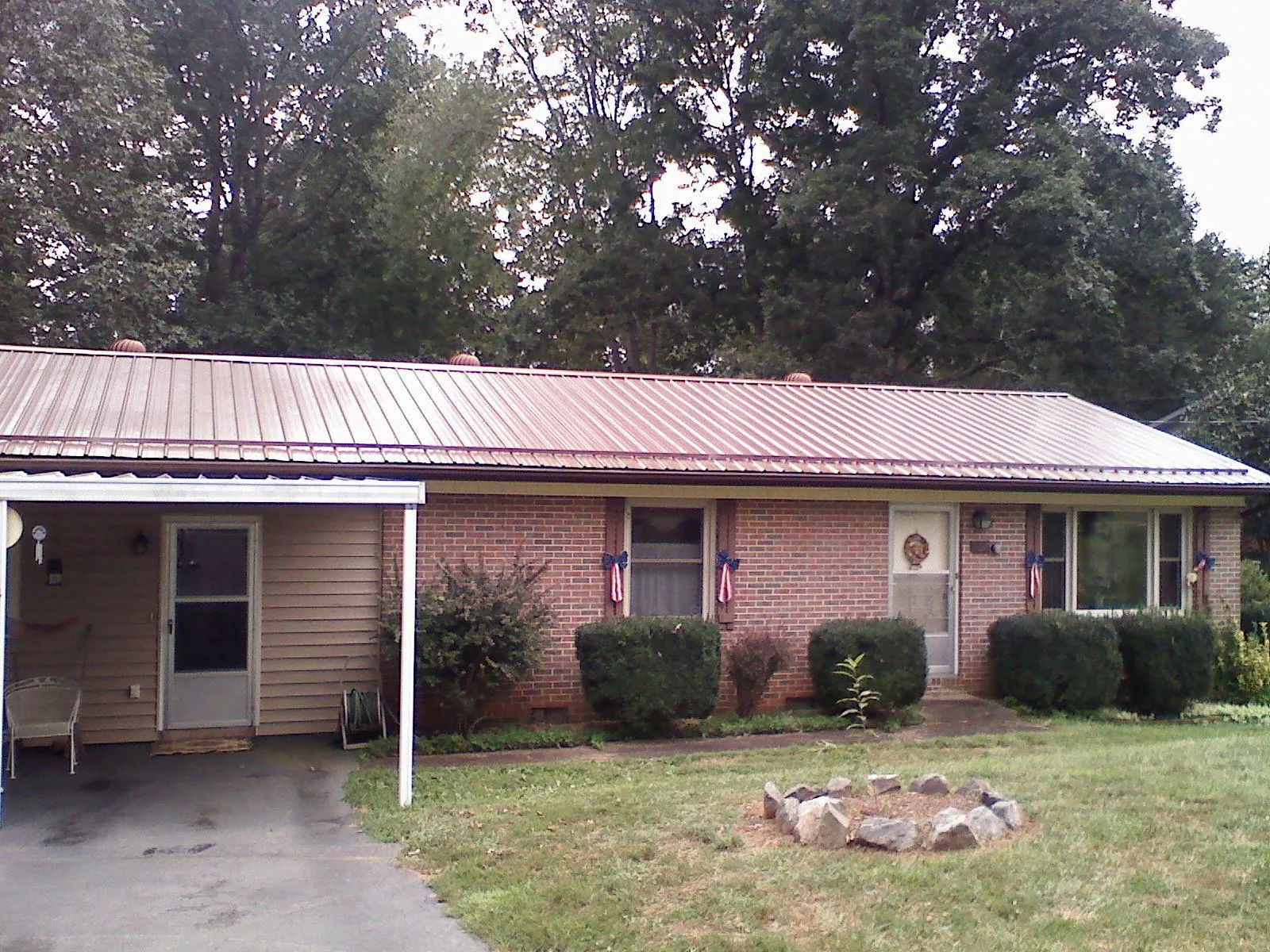 Bronze metal roof and carport on a brick ranch home — Roof Repair work by our crew in Mustang