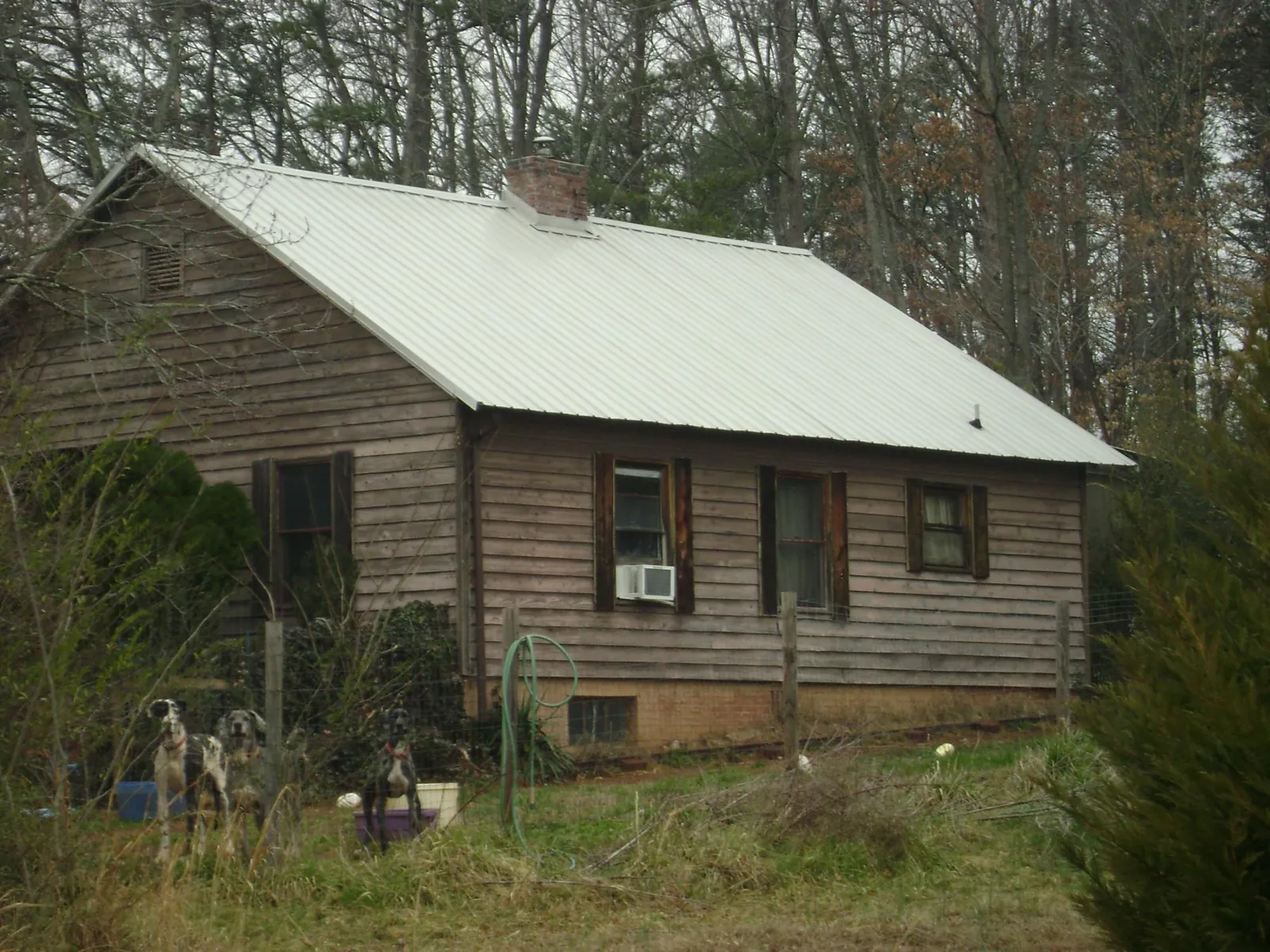 White metal roof on an old wood sided farmhouse, from a Metal Roof Installation job in Mustang