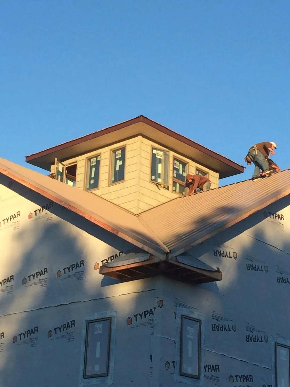 Roofers working around a rooftop cupola on a new metal roof at sunset — Roof Waterproofing in Mustang by Roofing Brothers